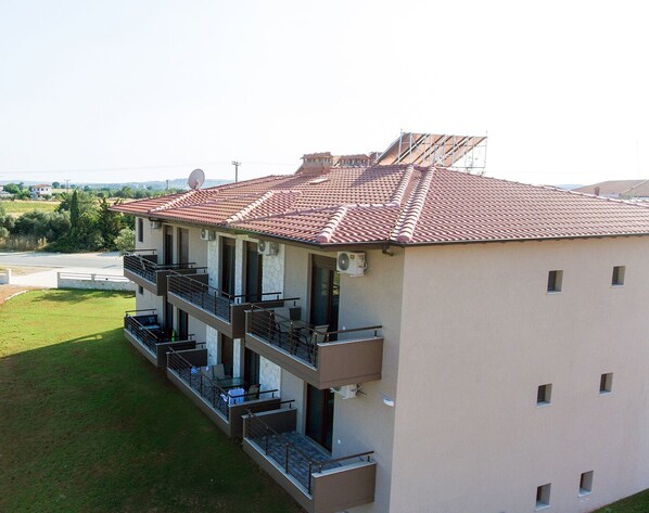 A multi-story building with balconies, satellite dishes, and a red-tiled roof.