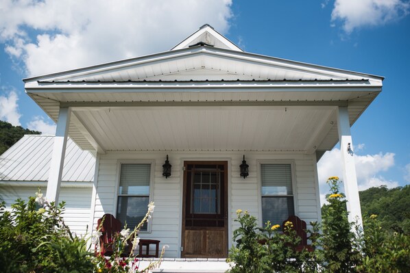 A white colonial-style house with a gabled roof, a front porch, and a wooden door. - Mountain serenity!!! (Independence)