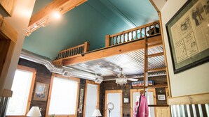 Een kamer met een houten plafond, een stapelbed, een kroonluchter en een lijst met een afbeelding aan de muur.