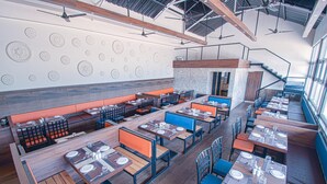 A modern restaurant with high ceilings, exposed beams, and a mix of wooden and upholstered seating. - Hotel Park Tree (Kolhapur)