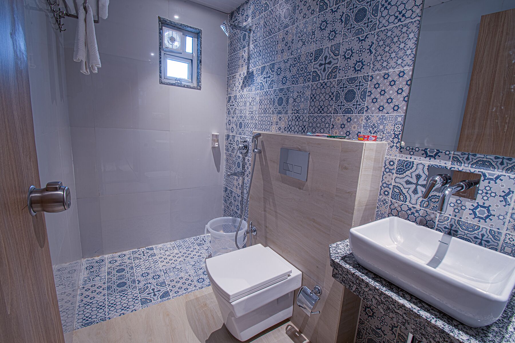 A bathroom with a shower, toilet, and sink, featuring blue and white patterned tiles.