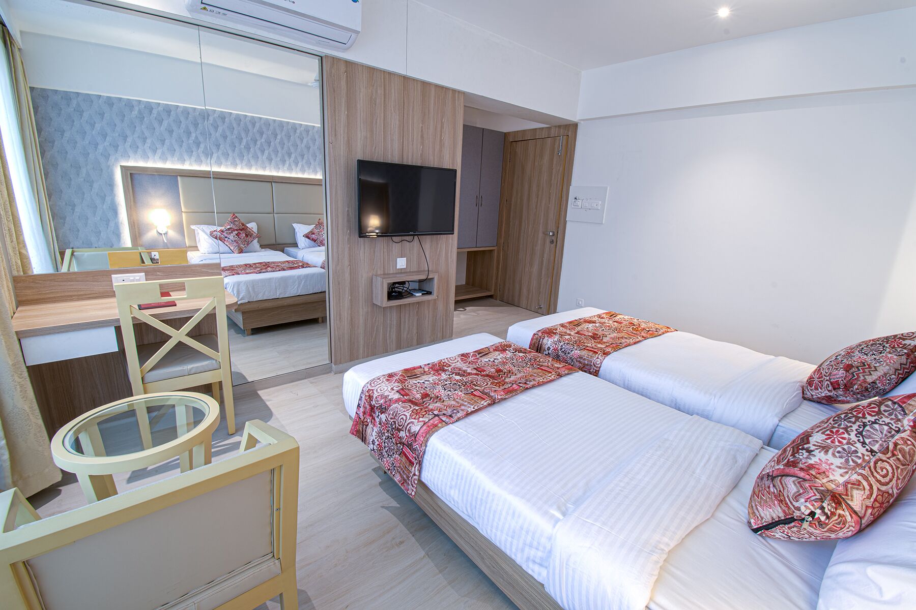 Habitación de hotel moderna con una cama grande, televisión, escritorio y espejo.