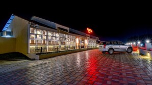 A restaurant with outdoor seating and a car parked in front. - Hotel Park Tree (Kolhapur)