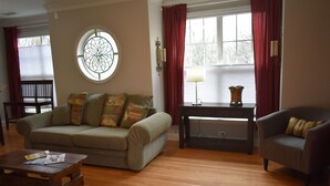 A living room with a sofa, armchair, wooden coffee table, and a side table with a lamp. - Special Pricing Uptown Condo Minutes from Bank of America Stadium (Charlotte)