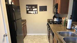 Cocina equipada con refrigerador, estufa, microondas y pileta. Se observan tapones de corcho y un calendario en la pared.
