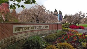 A sign for the University of Portland with a brick wall and flowering plants. - Dragonfly House-One Bedroom Craftsman in Trendy Kenton (Portland)