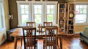 A dining area with a wooden table and chairs, a bookshelf, and a globe. - Dragonfly House-One Bedroom Craftsman in Trendy Kenton (Portland)