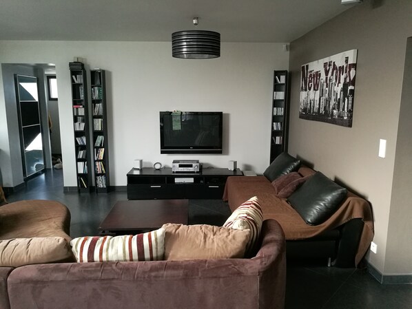 Una sala de estar moderna con un sofá, una mesa de centro, un televisor y una estantería.