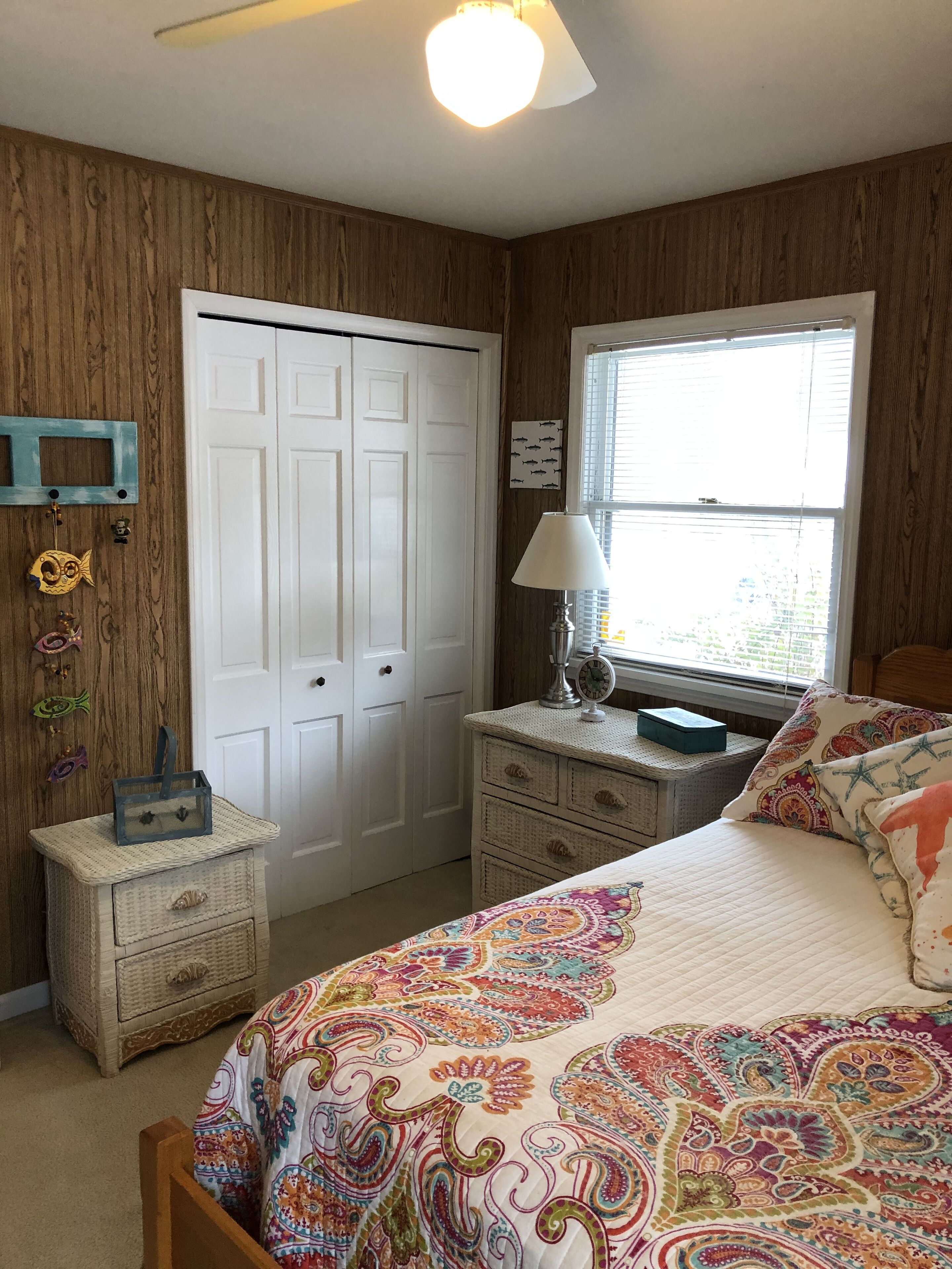 Une chambre à coucher avec un lit, une commode et une fenêtre équipée de stores.