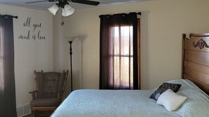 A bedroom with a bed, a chair, a ceiling fan, a window with curtains, and a wall with a motivational quote. - Country Serenity at The Resting Windmill (Mauston)