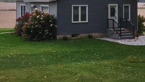 A two-story house with a dark gray exterior, white trim, and a black front porch. - Country Serenity at The Resting Windmill (Mauston)
