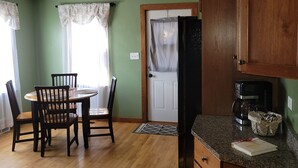 A kitchen with wooden cabinets, a refrigerator, and a dining table with chairs. - Country Serenity at The Resting Windmill (Mauston)