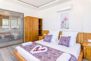 A modern bedroom with a large bed, wooden wardrobe, and a glass shower enclosure.