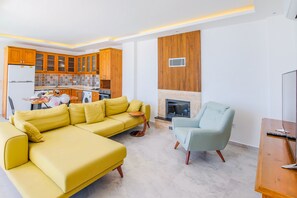 A modern living room with a yellow sofa, a light blue armchair, and a fireplace.