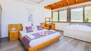 A bedroom with a wooden bed, a wooden nightstand, a wooden dresser, a large window with a view of the outdoors, and a white bathtub.