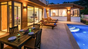 A modern house with a pool, wooden deck, and outdoor seating area.