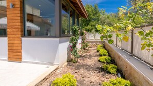 A modern house with large windows, a wooden exterior, and a garden with various plants and flowers.