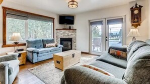 A living room with a fireplace, a television, and a clock on the wall. - Mountain Comfortable Colorado Lodging in Frisco CO - Sleeps 8 - 1 block off Main (Frisco)