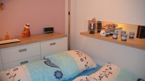 Une chambre à coucher comprenant un lit, une table de chevet, une étagère avec des objets décoratifs et une étagère fixée au mur.