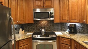 A kitchen with wooden cabinets, a stainless steel refrigerator, a microwave, a stove, and a coffee maker. - Beautiful Marriott Timeshare Unit located adjacent to JW Marriott (Palm Desert)