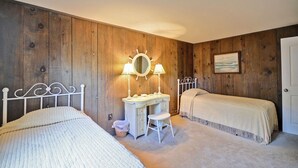 Un dormitorio con dos camas, un escritorio con silla, un espejo y un cuadro en la pared.