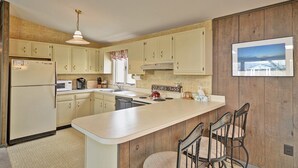 Una cocina con una isla central, armarios de madera, un refrigerador, una estufa y un fregadero.