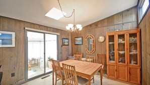 Un comedor con una mesa y sillas de madera, una araña y un aparador con puertas de cristal.