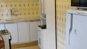 A compact kitchen with white cabinets, a microwave, and a refrigerator. - Ed. HSS (Ouro Preto)