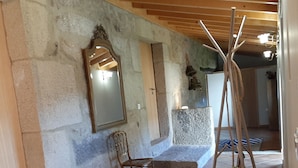 Una stanza con parete in pietra, soffitto in legno, uno specchio, una sedia, un tappeto a motivi zebrati e un termosifone.