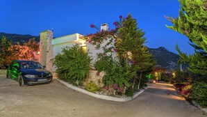 Una casa moderna con entrada, un coche y zonas verdes alrededor.