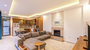 A modern living room with a sectional sofa, a dining area, and a kitchen with wooden cabinets.