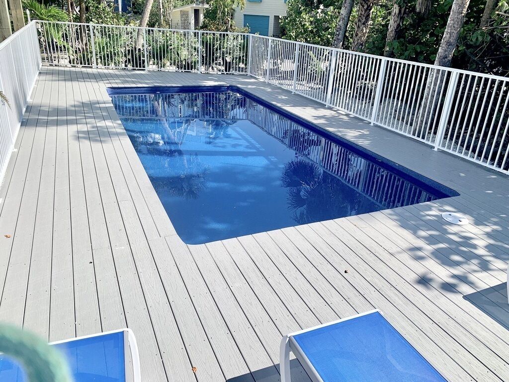 Una piscina con cubierta de madera y barandillas blancas.