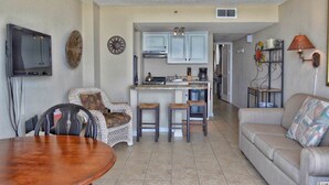 A living room with a sofa, a dining table, and a kitchen area with a central island. - Gorgeous Oceanfront Condo With Direct Ocean View (Myrtle Beach)
