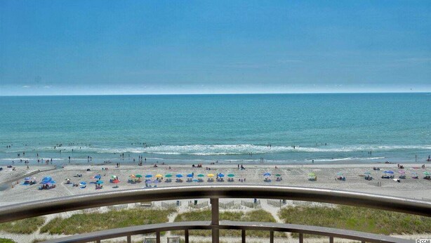 A beach with umbrellas and people, a clear sky, and a view of the ocean. - Gorgeous Oceanfront Condo With Direct Ocean View (Myrtle Beach)