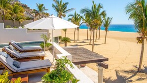 A beach resort with a pool area, lounge chairs, and palm trees. - Thanksgiving Promo!!  Your Exclusive Cabo Beachfront Escape (Cabo San Lucas)
