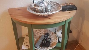Une petite table en bois, sur laquelle se trouve un panier en osier, une télécommande et un décodeur.