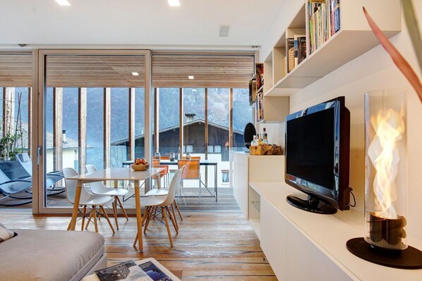 Een moderne woonkamer met een eethoek, een televisie en een open haard.