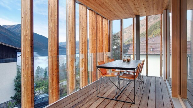 A modern room with a wooden floor and large windows offering a mountain view.