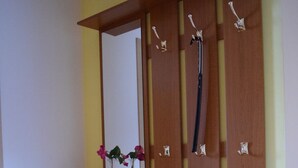 Un armario de madera con espejo, estantes varios y ganchos.