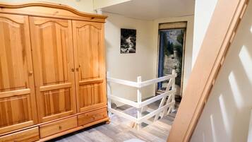 Un dormitorio con un armario de madera, una cama blanca y vista a un jardín a través de una puerta.