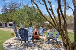 An outdoor seating area with chairs and a table, surrounded by a stone patio. - Casa del Rio | Pet-Friendly River Stay with Views (Bandera)