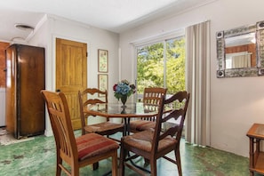 A dining area with a glass table, wooden chairs, and a vase of flowers. - Casa del Rio | Pet-Friendly River Stay with Views (Bandera)