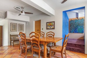 A dining area with a wooden table and chairs, a ceiling fan, and artwork on the walls. - Casa del Rio | Pet-Friendly River Stay with Views (Bandera)