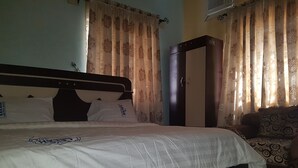 Ein Schlafzimmer mit Bett, Kleiderschrank und Vorhängen.
