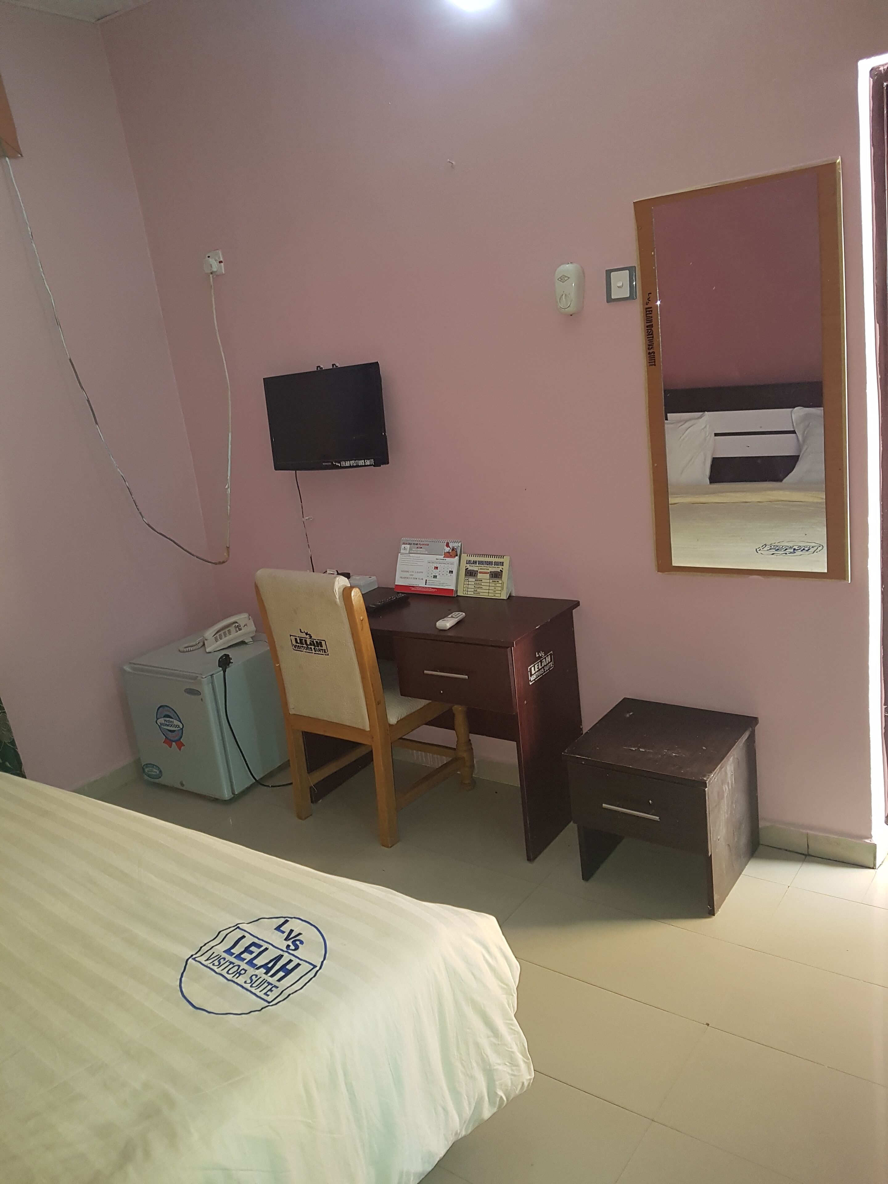 A room with a bed, a desk, a chair, a television, and a small cabinet.