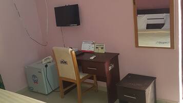 A room with a bed, a desk, a chair, a television, and a small cabinet.