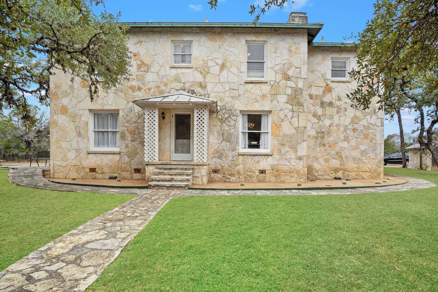 A stone building with a central entrance, a covered porch, and a stone pathway leading to the entrance.