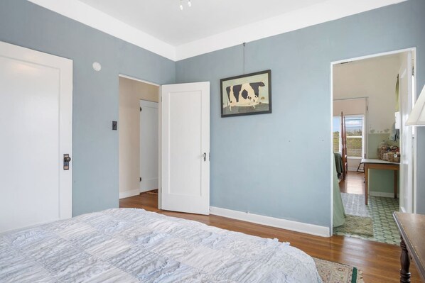 A bedroom with a bed, a door, and a hallway leading to a bathroom. - Hacienda del Rio | Historic Home on Medina River (Bandera)