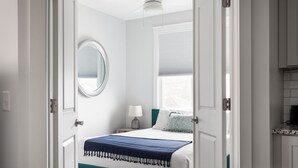 Una camera da letto con un letto, un comodino, una lampada e una finestra con tende.
