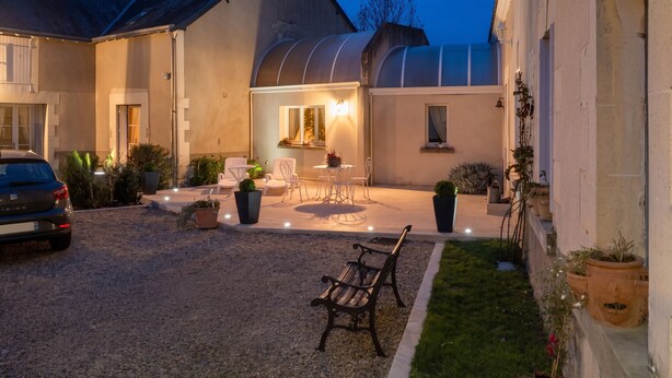 A gravel patio with outdoor seating, a car, and a building with a curved roof. - Homerez - Studio in Thilouze (Thilouze)